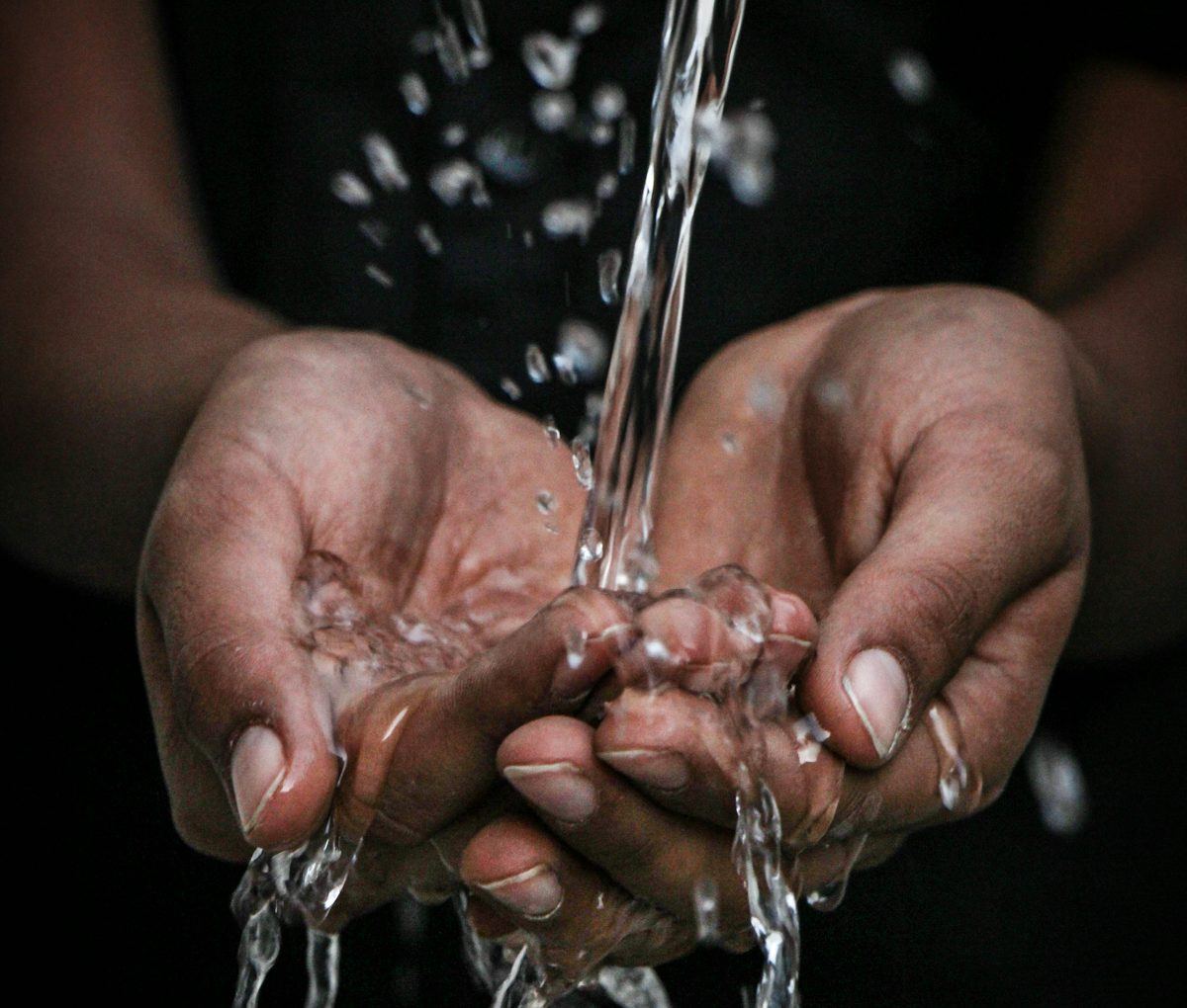 Clean water poured into a person's cupped hands from an Arid atmospheric water generator